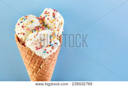 Ice Cream Balls With Colored Sugar Sprinkles In A Waffle Cone On A Blue Background. Vanilla Ice Crea