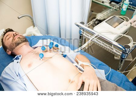 Young Man Lying On Bed With Ecg Electrodes Placed In His Chest