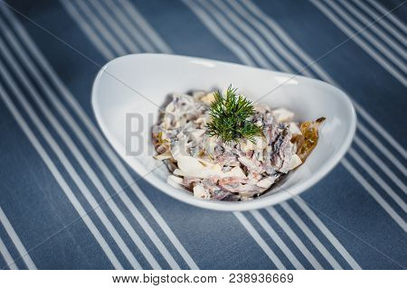 Top View Of A Salad In The White Plate On The Table With A Blue Tablecloth In White Strips. Salad Of