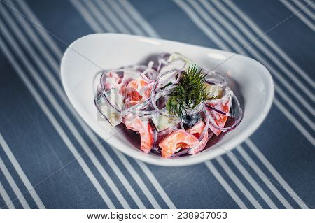 Top View Of A Salad In The White Plate On The Table With A Blue Tablecloth In White Strips. Salad Of