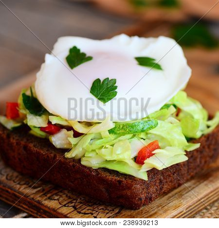Quick Egg Poached Sandwich. A Poached Egg On A Rye Bread Slice With Fresh Cabbage, Cucumber, Pepper 