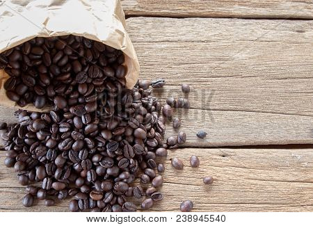 Top View With Roasted Coffee Beans In Paper Bag On Wood Table Background Area For Copy Space. Coffee