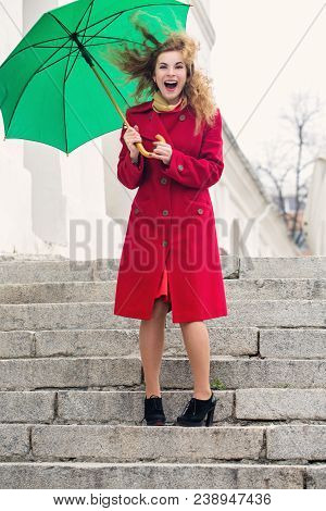 Young Cheerful Woman Under An Umbrella In The Wind