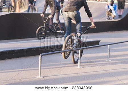 Two Cyclists On Bmx Bikes Do Tricks In A Park Skate. Bike Skater Slides On Bmx By Perel. Training Of