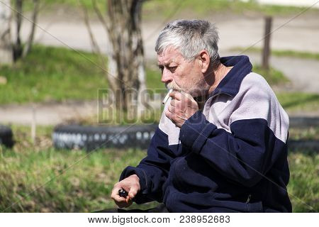 Gray-haired Old Bearded Man Smoking A Cigarette Without A Filter