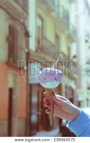 A Woman Sitting And Holding An Ice Cream. Summer Time In The Street Of The Old City. Vertical Orient