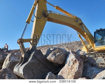 Excavator Is Moving A Rock Boulders During Road Construction On The Rocky Soils