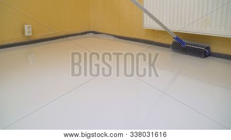 Worker Rolls Liquid Floor. Needle Roller For Bulk Floors. A Worker Fills The Floor With A Needle Rol