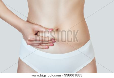 A Woman Shows Body Fat On Her Stomach. Overweight Treatment And Athletic Lifestyle. Cosmetology Conc