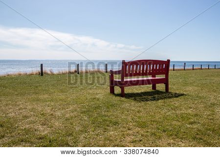 Empty Red Bench On The Seashore At Point Prim Lighthouse,  Prince Edward Island, Canada
