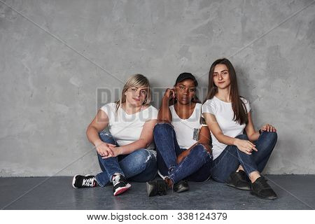 Calm Atmoshphere. Group Of Multi Ethnic Women Sitting In The Studio Against Grey Background.
