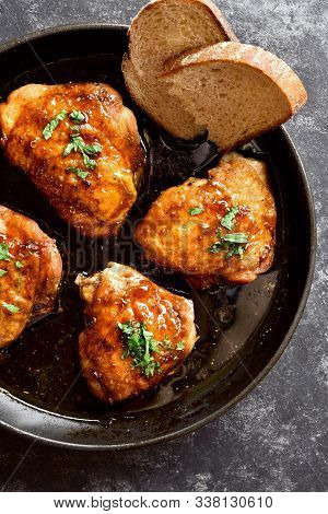 Grilled Chicken Thighs In Frying Pan Over Dark Stone Background. Tasty Food In Asian Style. Top View