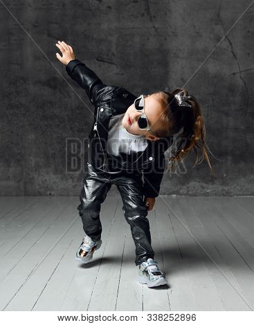 Cool Frolic Kid Girl In Leather Jacket, Jeans And Sunglasses Is Having Fun Modern Dancing Playing Ru