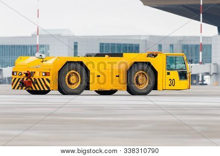 Airplane Yellow Pushback Truck In Moving At Airport. Special, Low Profile Vehicle - Pushback Tractor