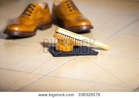 Pair Of Luxury Male Full Brogued Tan Oxford Shoes. Placed Together With Shoe Wax And Brush On Tiles 