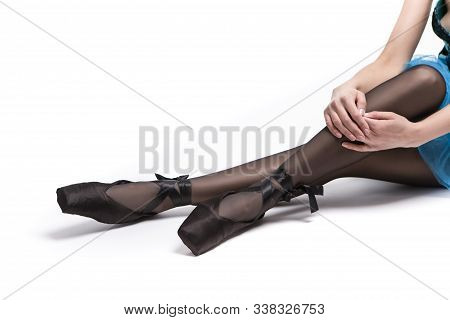 Closeup Of Legs Of Caucasian Ballet Dancer In Blue Tutu And Pointes Shoes Against White Background. 