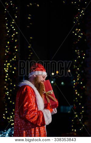 Bad Santa Claus On The Background Of Christmas Decorations. A Man In A Suit Of Santa Claus After The