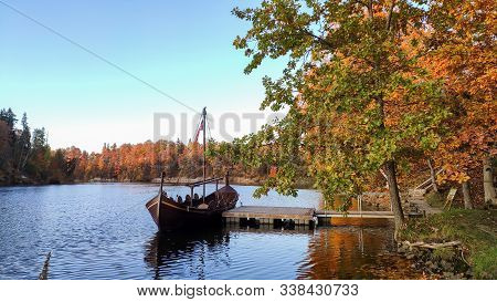 The Tourist Boat In The Style Of A Viking Ship On The River Perse. Autumn Old Koknese Castle Ruins. 