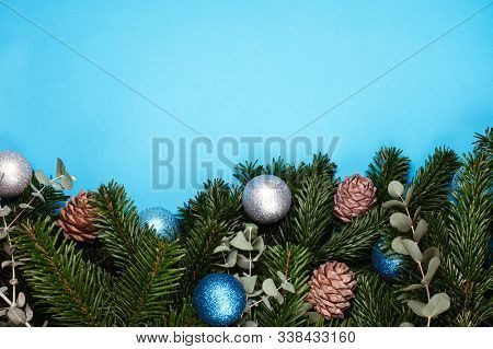 Banches Of Pine Tree On Blue Background With Christmas Balls And Pine Cones. Place For Text.