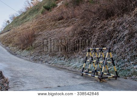 Yellow And Black Moveable Road Gate On Side Of Mountain Road.