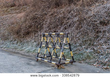 Yellow And Black Moveable Road Gate On Side Of Mountain Road.