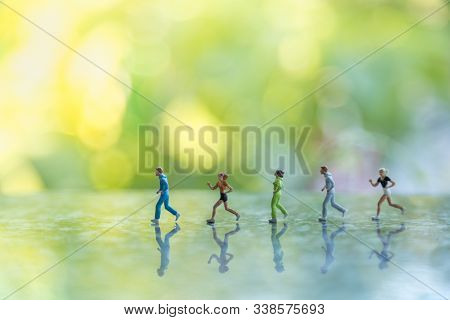 Fitness And Sport Concept. Group Of Runner Miniature Figure People Running On Ground With Green Leaf