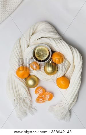 Lemon Tea Is Wrapped In A White Knitted Scarf On A White Background With Tangerines And Christmas Go