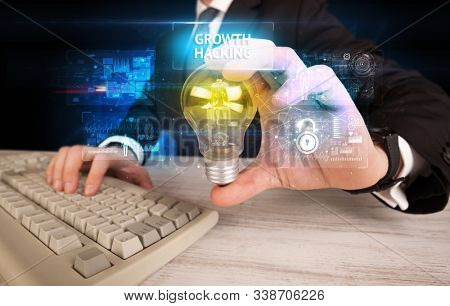 Businessman holding lightbulb with GROWTH HACKING inscription, online security idea concept