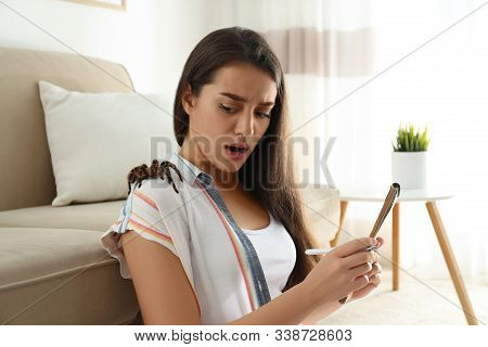 Scared Young Woman With Tarantula At Home. Arachnophobia (fear Of Spiders)