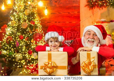 Adorable Child Son Play With Santa Dad At Home. Winter Holidays. Santa Boy Celebrate Christmas At Ho