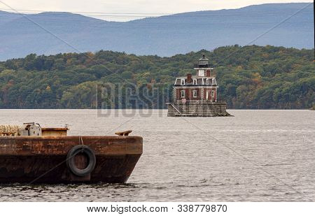 A Rusty Old Barge Sits In The Foreground Near The Hudson Athens Lighthouse In Upstate New York Usa