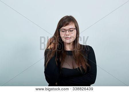 Surprised Cheerful Young Woman In Casual Black Dress, Looking Down, Holding Hand In Hair, Having Cas
