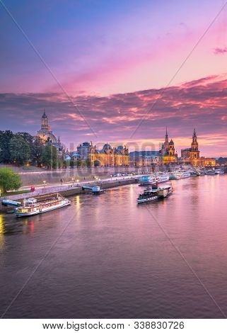 Dresden, Germany cityscape of cathdedrals over the Elbe River at dusk.