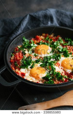 Traditional  Shakshuka With Eggs, Tomato, And Parsley In A Iron Pan On A Dark Background. Top View.