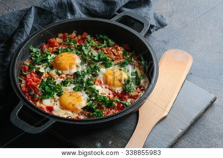 Traditional  Shakshuka With Eggs, Tomato, And Parsley In A Iron Pan On A Dark Background. Top View.