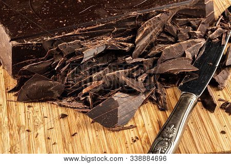 Big Chocolate Bar Cut Into Pieces With Knife On A Wooden Chopping Board