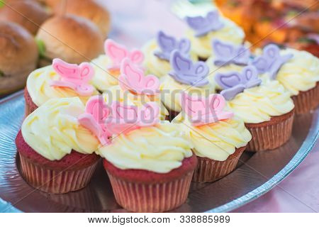 Close-up Of Red Velet Cupcakes With White Cream Cheese On Top Decorated With Colorful Butterflies. C