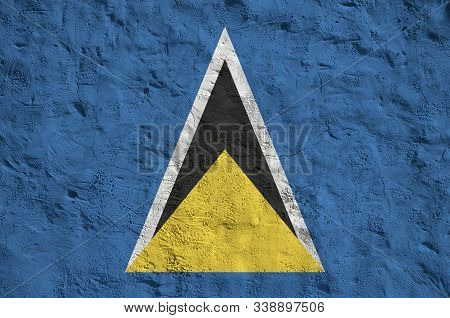 Saint Lucia Flag Depicted In Bright Paint Colors On Old Relief Plastering Wall. Textured Banner On R