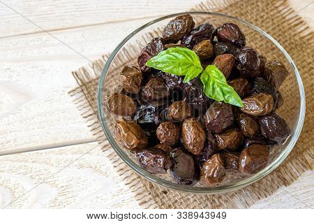 Sun-dried Or Cured Olives In A Glass Bowl On A White Rustic Wooden Table. Healhy Eating And Vegetari