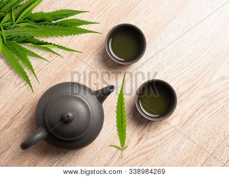 Tea Made From Cannabis Leaves ,a Glass Of Hot Marijuana Tea On Wooden Table , Tea Pot And Cups On Wo