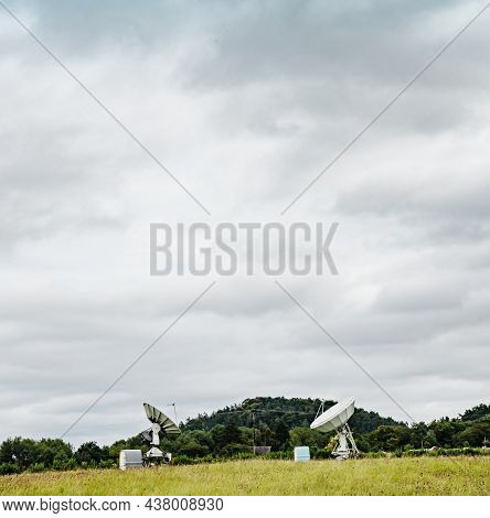 Large Radio Telescope Is Situated Under Green Hills Against Cloudy Sky