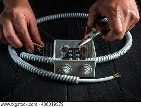 Close-up Of Hands Of Master Electrician During Work. Installing A Cable Or Wire To Gray Junction Box
