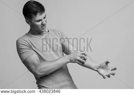 Despaired Millennial Caucasian Male Suffering From Irritation And Scratching Skin On Hand With Painf
