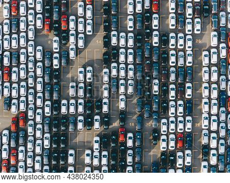 New Multi-colored Passenger Cars Stand In Straight Rows On A Giant Paved Marked Parking Lot On The T