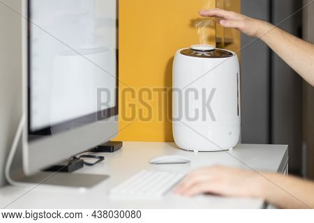 White Air Humidifier Spreading Steam. Humidification Of Dry Air While Man Working On Computer. Selec