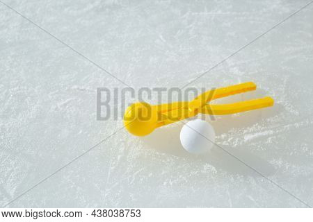 A Snowball With A Yellow Plastic Tool For Modeling Snowballs Lies On An Ice Rink On A Sunny Frosty W
