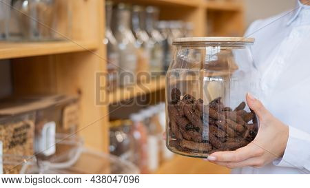 A Woman Holds Croutons In A Glass Jar. Eco Shop Without Plastic Waste.