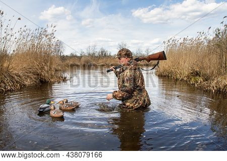 The Hunter Is Walking In The Middle Of The Lake, Waist-deep In Water. He Collects Plastic Bait For D