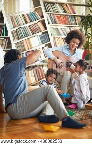Young family enjoying the guitar and the music in a cheerful atmopshere at home. Family, together, love, playtime