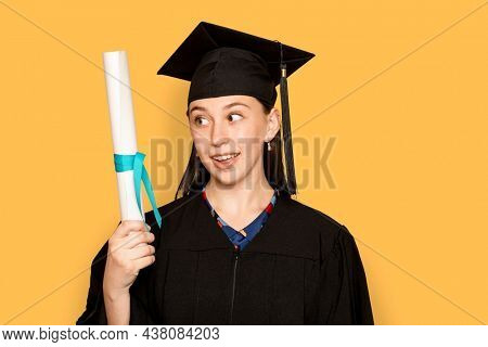 Woman wearing regalia holding her degree for graduation